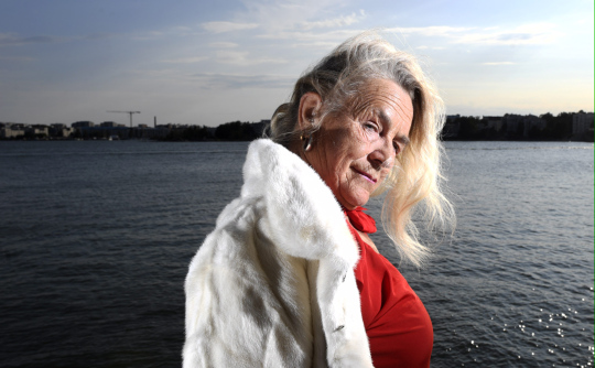 Taiteilija Miina Äkkijyrkkä poseeraa kuvaajalle rannan läheisyydessä.