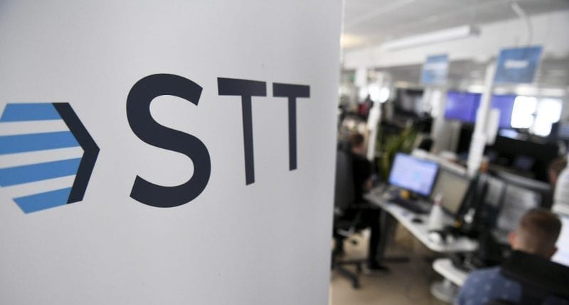 STT:n toimittajia töissä tietokoneiden ääressä, vasemmassa laidassa STT:n logo
