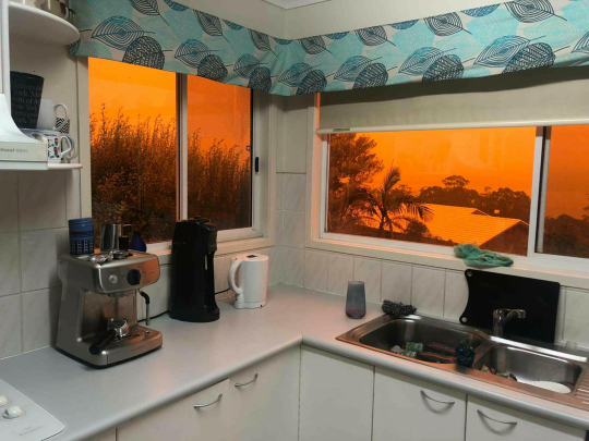 Australian maastopalojen oranssi kajo keittiön ikkunoiden läpi.