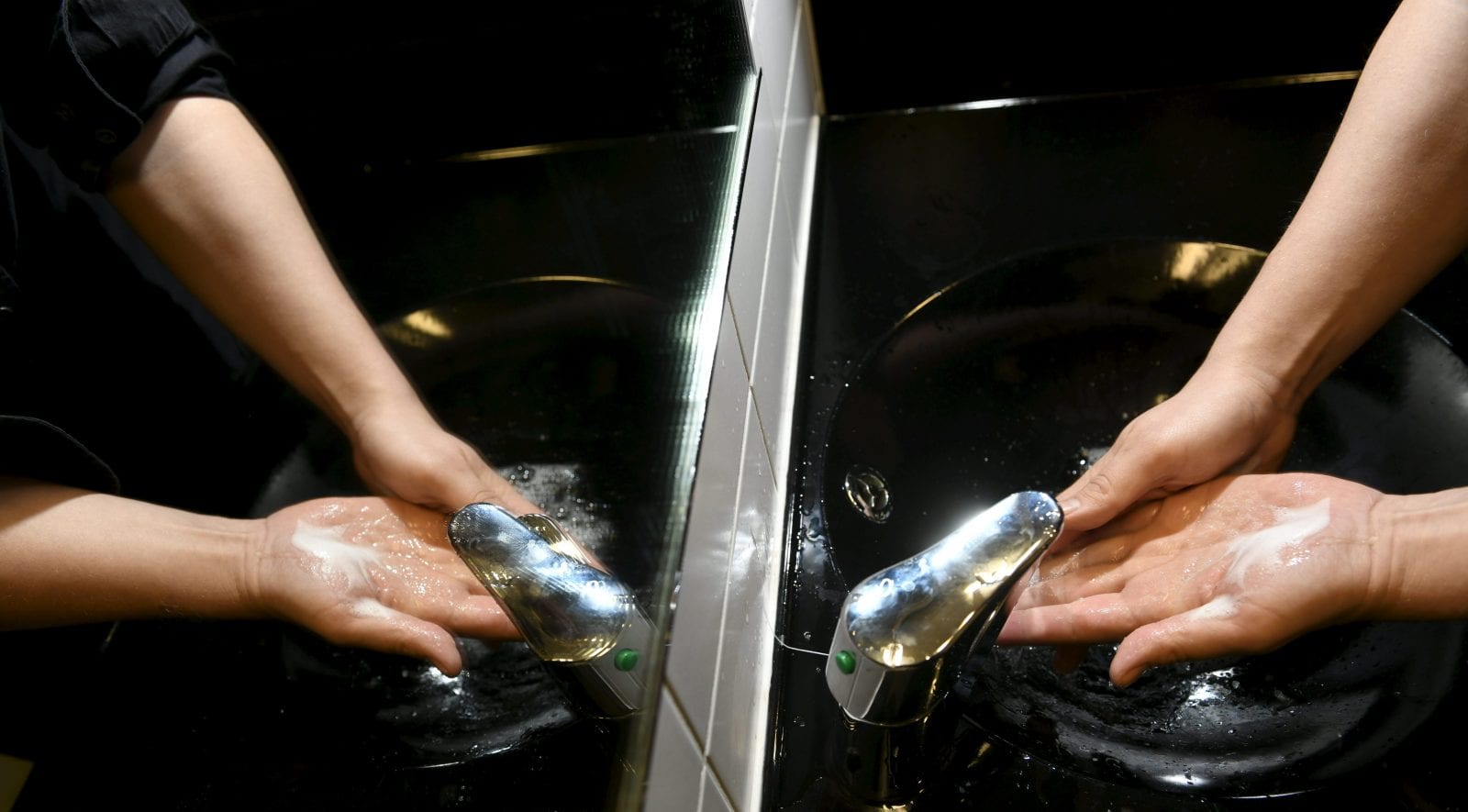 Mies pesee käsiään lavuaarissa.