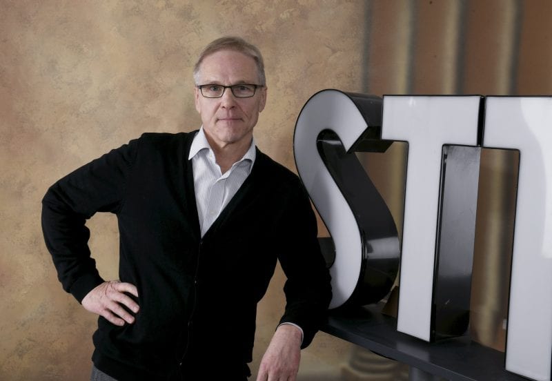 Kimmo Pietinen poseeraa STT:n logon edessä.