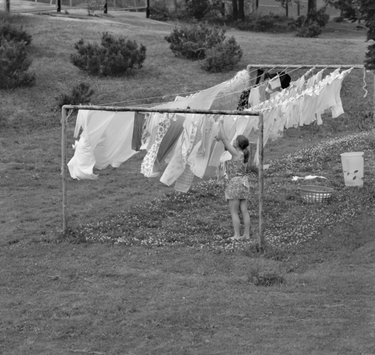 Nainen ripustaa pyykkiä kuivumaan pyykinkuivaustelineelle.